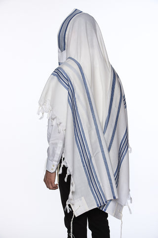 Person wearing a white and blue striped prayer shawl on a white background
