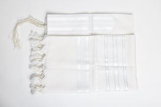 White prayer shawl with fringe on a light gray background